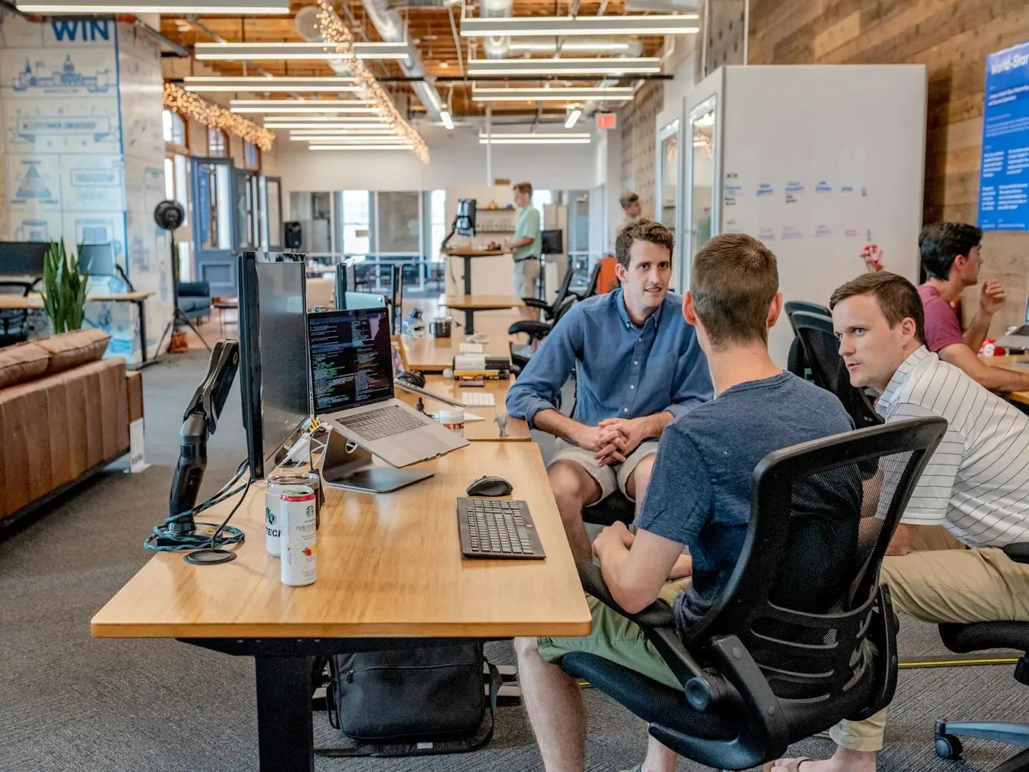 Team talking at desks with laptops and monitors – managed IT in everyday office work